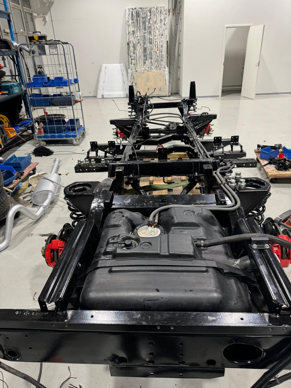 Chassis on workshop floor — fuel tank installed, looms routed